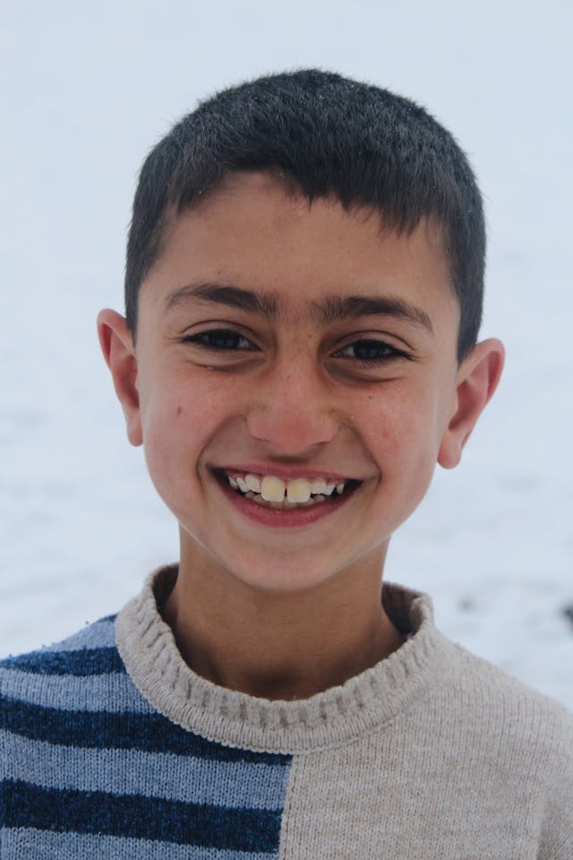 A child smiles brightly, full of warmth and resilience